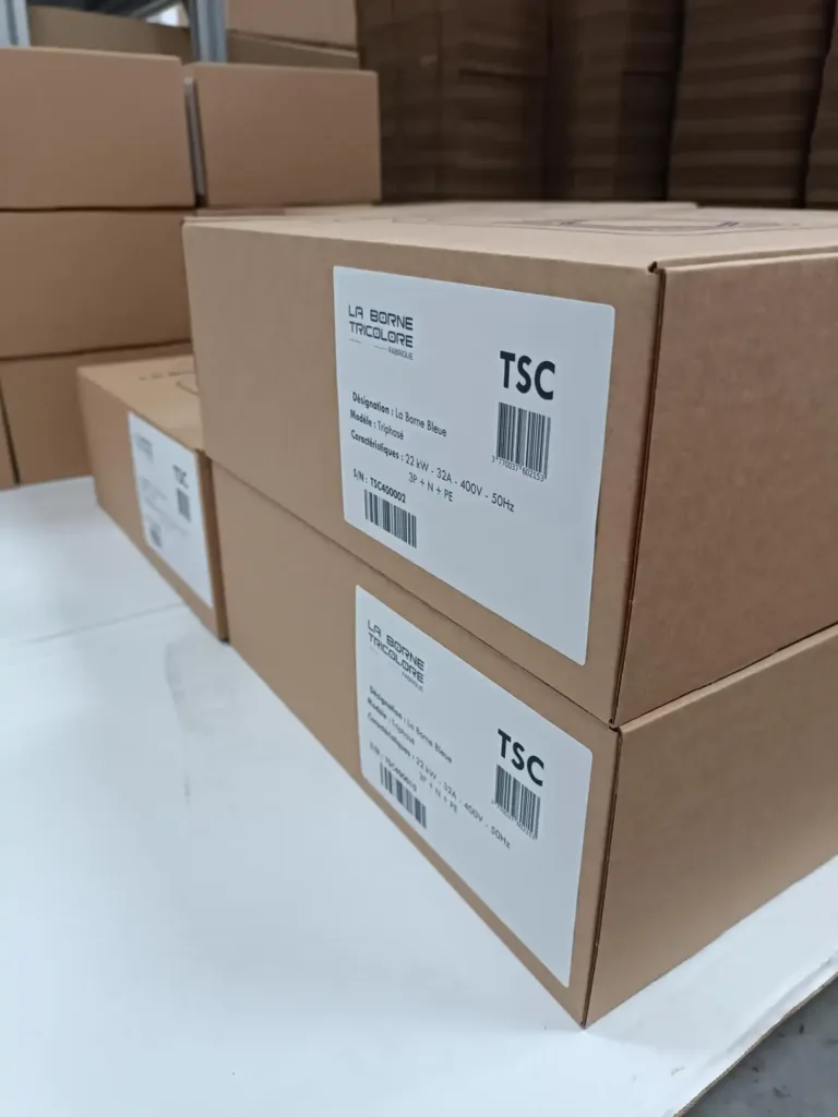 Stack of brown cardboard boxes on a warehouse shelf, each with labels showing TSC and La Borne Tricolore.